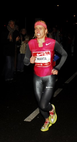 Memento Mori. El vértigo de la victoria, el deslumbramiento del éxito produce náuseas, es difícil vivir en un mundo de mortales cuando se ha rozado el paraíso, es difícil regresar al inframundo, al Hades, cuando se habita en los Campos Elíseos. Marta Domínguez fue utilizada por el poder (a ella no le importó, fue senadora por el PP) como ejemplo de persona luchadora, íntegra, de atleta entregada al sacrificio de la perfección, al sacerdocio del deporte purificador. Quizás midió mal sus capacidades y resbaló a punto de entrar en la meta de los triunfadores, se quedó a tres pasos de la gloria. Pasó de heroína a villana, de representar el éxito a equipararse al engaño, al fraude, su carrera política se arruinó, su carrera deportiva no tiene crédito. El pasado 19 de noviembre el Tribunal de Arbitraje del Deporte (TAS) la suspendió por tres años de la práctica deportiva (sin efectos posibles ya que estaba retirada de la competición) y la despojó de sus títulos deportivos por el uso de sustancias dopantes. Su caída a los infiernos de los falsos atletas, de los mentirosos, de los estafadores ha sido imparable, como Armstrong. En la foto aparece en la San Silvestre Vallecana, 31 de diciembre de 2009. Caronte aguarda vigilante en su barca sobre la laguna Estigia.