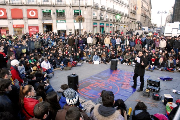 Alternativas que al poder le resultan sospechosas El poder tiene miedo de que se ocupe el suelo público para manifestarse en su contra. Por eso procura hacer incómodo su uso, bien despoblándolo de mobiliario urbano, ausencia de bancos donde se sienten los vecinos, bien colocando obstáculos e impedimentos -un ejemplo son las marquesinas antimendigos-, bien retirando árboles que den sombra en los tórridos veranos madrileños. Tanto en la Puerta del Sol, como en la Plaza del Callao no existen bancos para sentarse y muy pocos en la Plaza Mayor, pero eso no impidieron las manifestaciones espontáneas del 11 de mayo de 2011. Desde entonces, el poder se ha encastillado en leyes mordazas que limitan el libre derecho de expresión. En la foto, el profesor Juan Carlos Monedero da su clase en la Puerta del Sol a pesar del frío del 28 de noviembre de 2012.